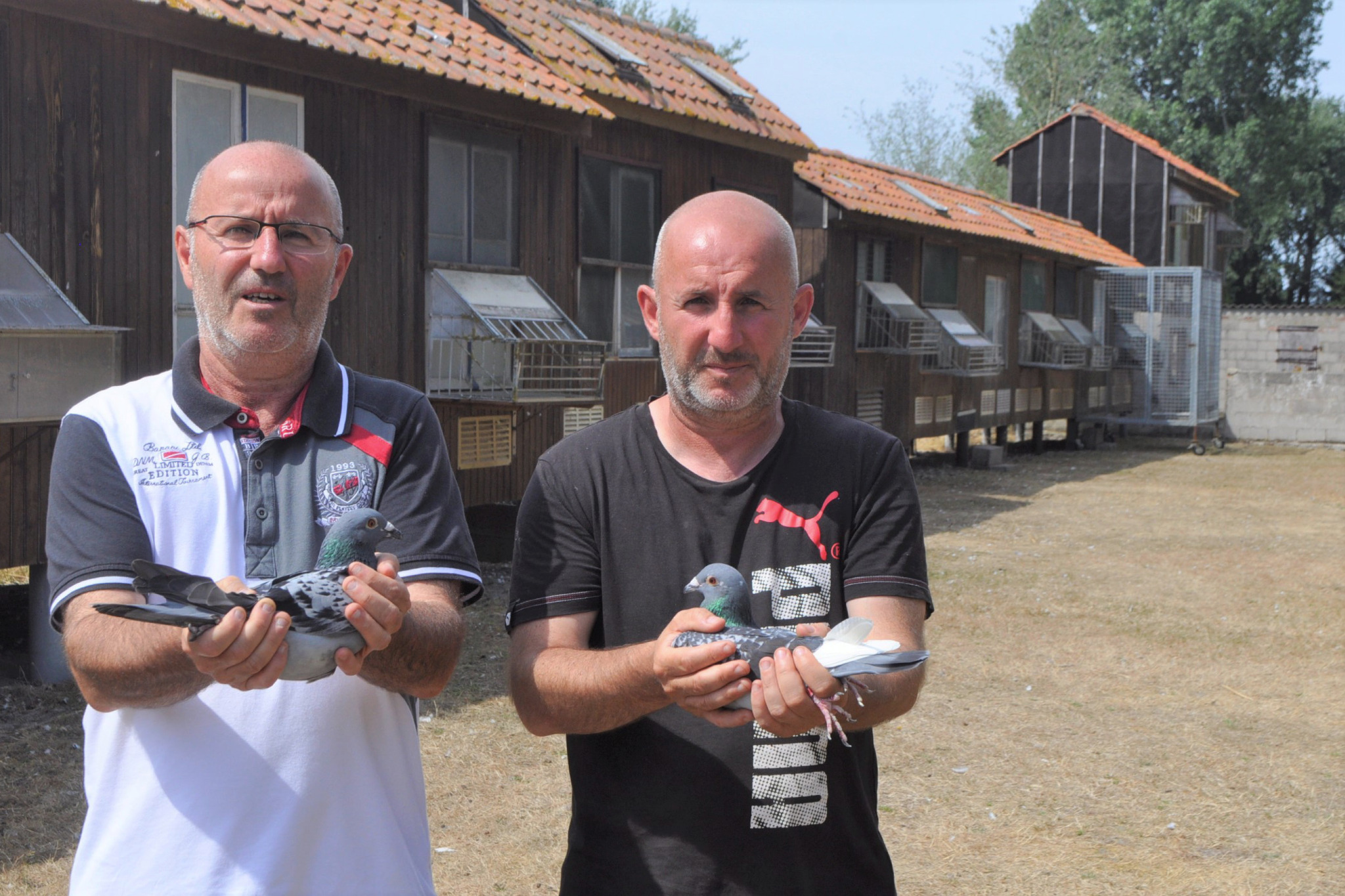 Les frères Rezenthel tenant chacun un pigeon devant leur colombier à Marck-en-Calaisis.